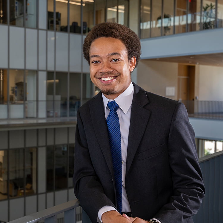 male student smiling and wearing a suit and tie