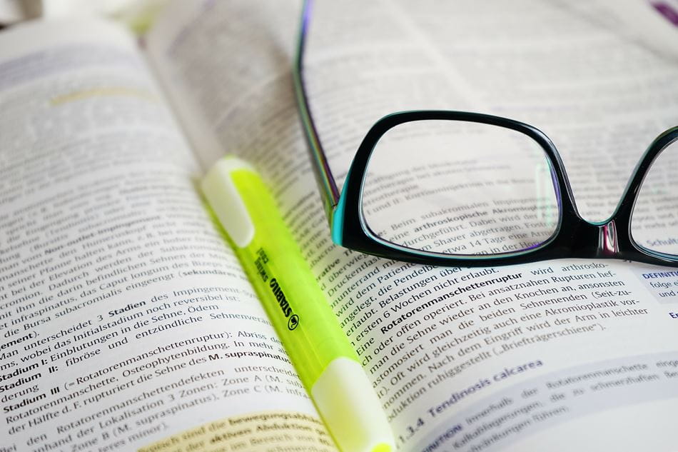 book open with highlighter and glasses