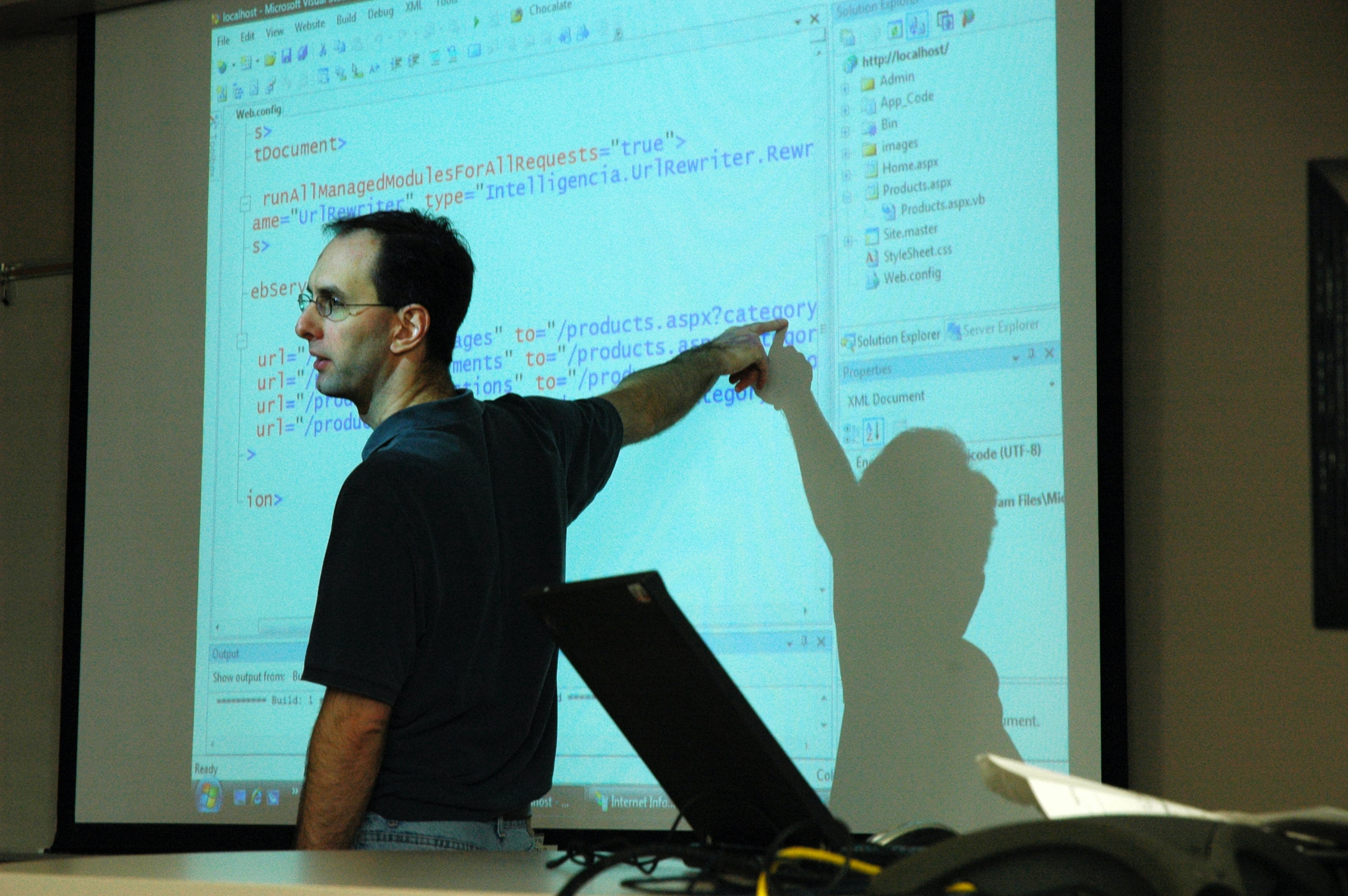 man lecturing in front of a screen 