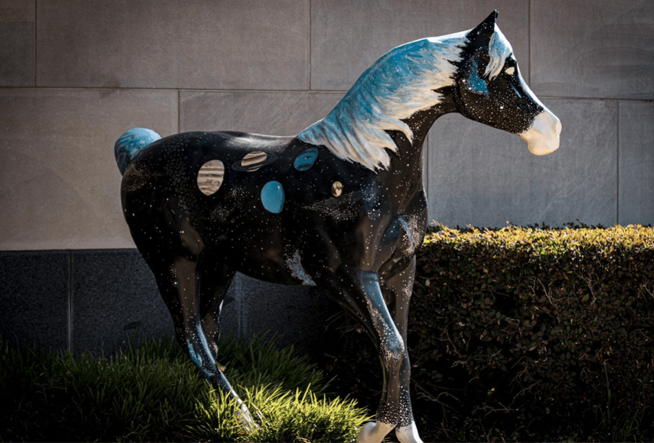 black horse statue with blue and white mane and planets on its body