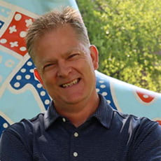 picture of Larry Nelson, dressed in a dark button up with his arms crossed in front of the U T A spirit horse by the M A C