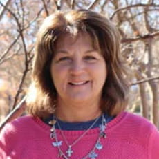 picture of Leeann Snell-Burke, dressed in a sweater over a shirt with a charmed necklace