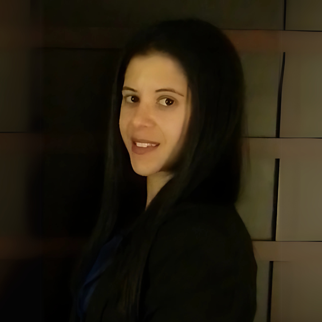 picture of Kathleen Tice, dressed in a blazer with a necklace on, posed in a children's classroom
