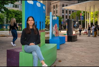 Angeles Margarida sitting next to a public art piece made by students