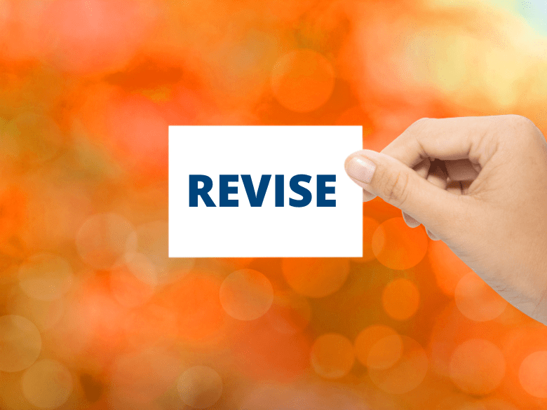 Hand holding sign that reads revise on orange background