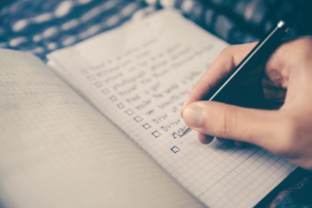 person writing a check off list in a journal