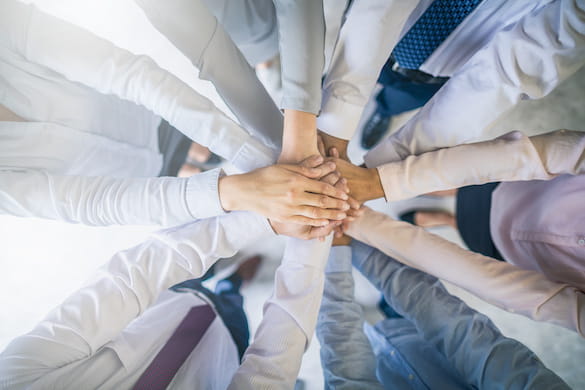 a group of people in a circle with their hands in the middle symbolizing a team