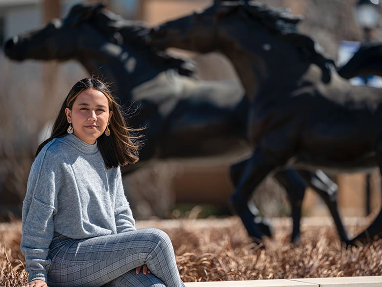 Student poses in front of the UC sculptures. 
