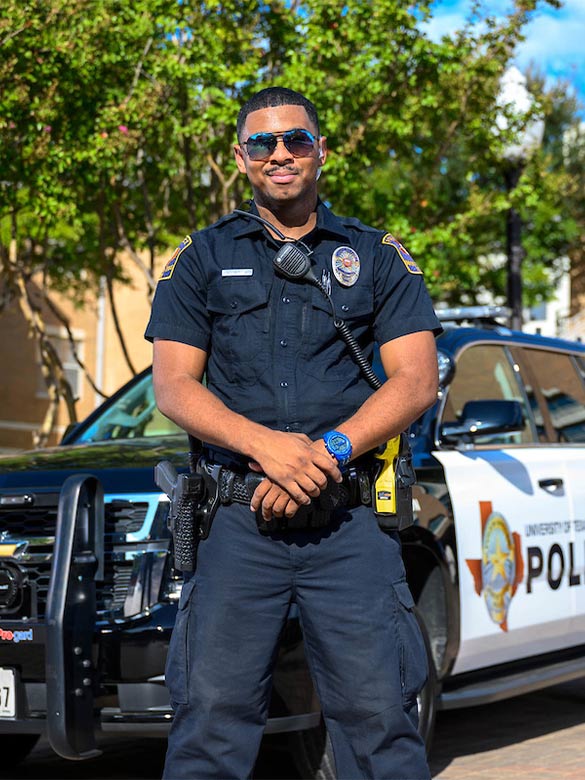 UTA Police Officer posing in front of UTA Police Vehicle. 