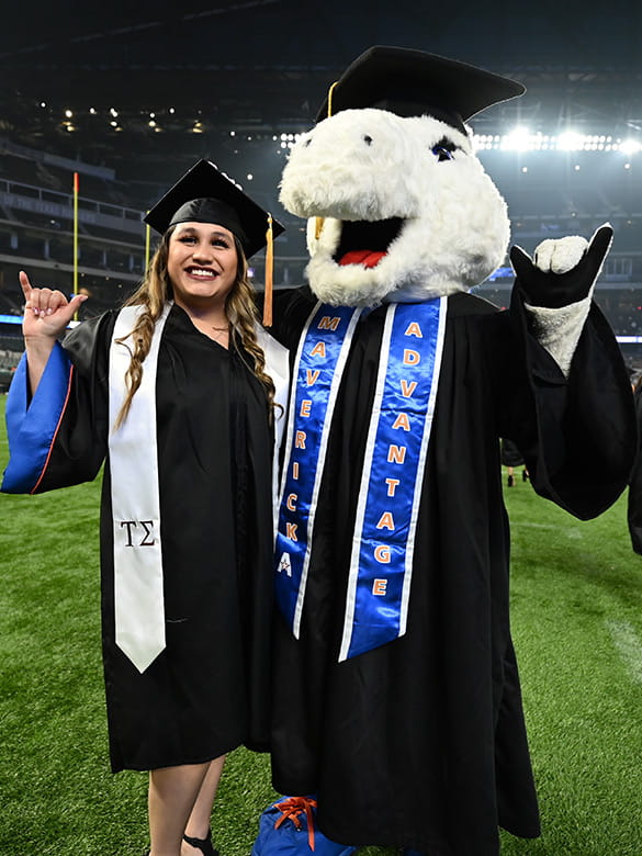 A student poses with Blaze at the 2021 Commencement. 