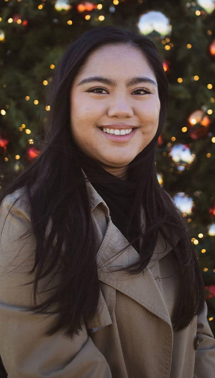 Student in front of a decorated Christmas tree