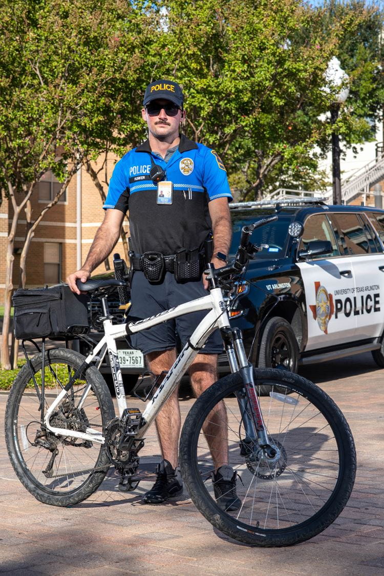 photo of police officer standing behind a bike