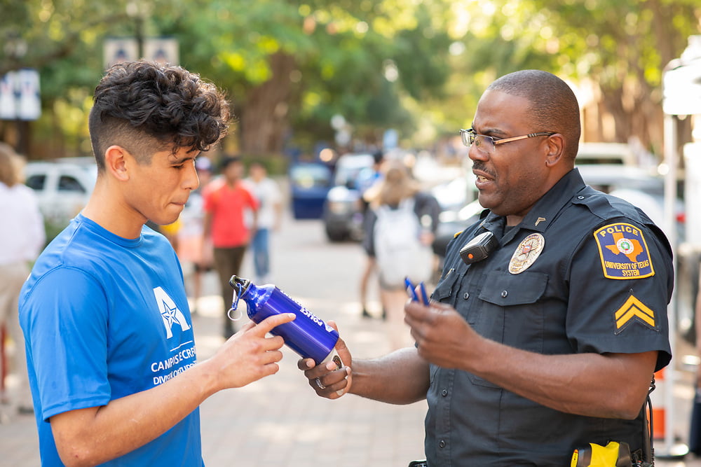photo of police officer handing a water bottle to a student
