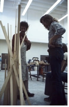 Students gathered around a wooden sculpture