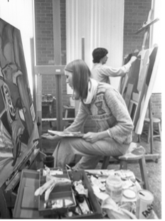 A black and white photo of a woman painting on a canvas
