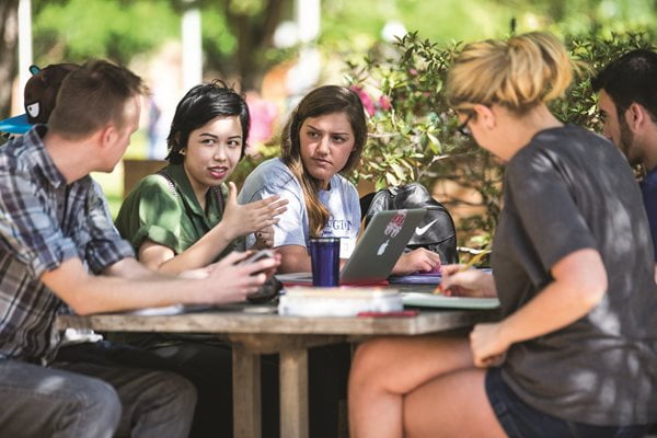 group of students sitting around a table outside.