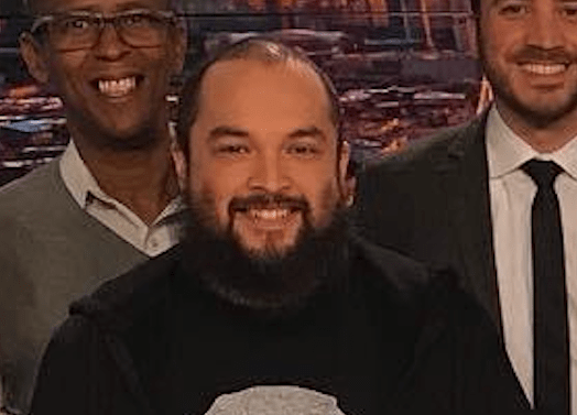 Omar Castillon in a news station, smiling with his coworkers