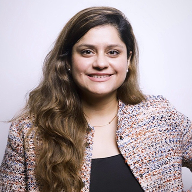 Ananya Singh smiling with long, wavy hair, jewelry, and plain top and jacket.