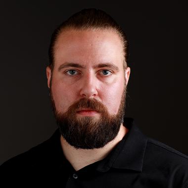 Doug Stark headshot, wearing a dark button down. He has a beard and very short hair.