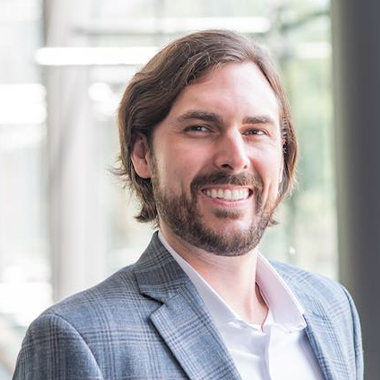 Peter Zuk wearing a suit with short-medium hair and a beard