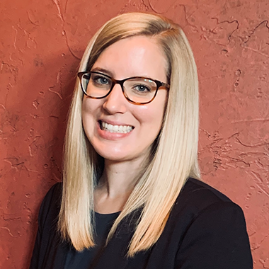Sara Collini smiling with medium-length straight hair and glasses