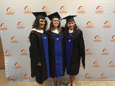 Three female students in regalia after their MA hooding