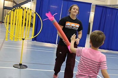 A Developmental Motor Cognition lab student works with a child in the Little Mavs Movement Academy.