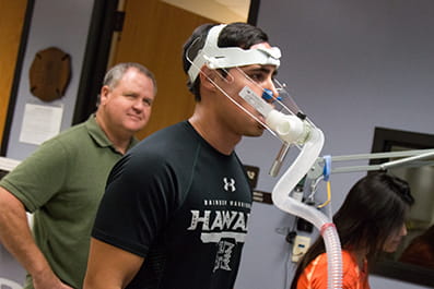 A runner wears a breathing tube and mask during a V O 2 max test. 