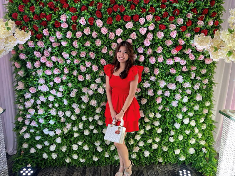 Christina Tan wearing a dress posing in front of floral background