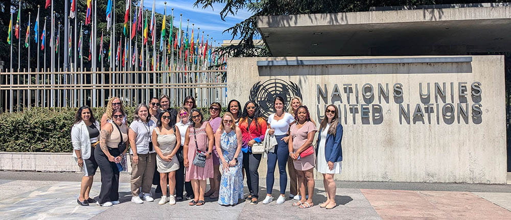 group of grad students and professors standing outside in front of United Nations and country flags