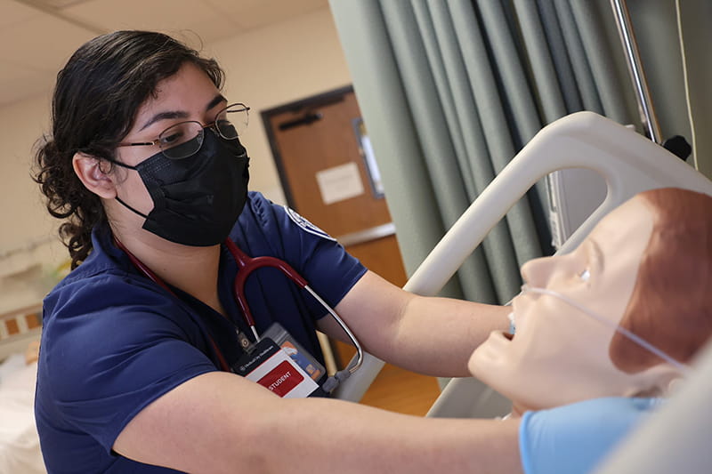 female nursing student working simulation mannequin