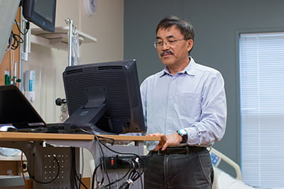 Dr. Yan Xiao working at computer in office