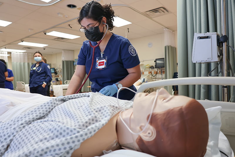 student nurse tending to medical manikin