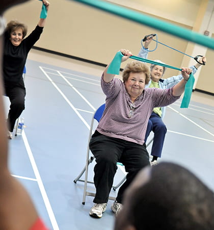 A group of older adults participate in a stretching exercise during an aerobics class.