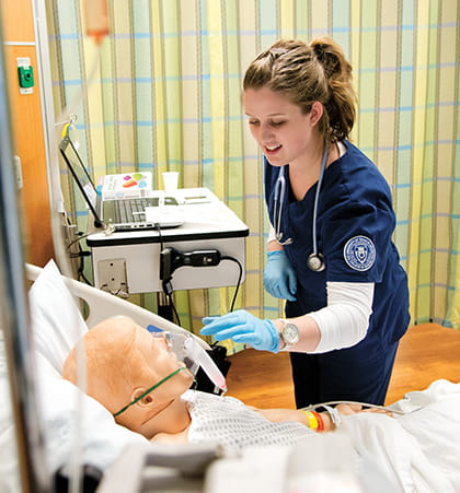 A nursing student adjusts an oxygen mask on a simulated patient.