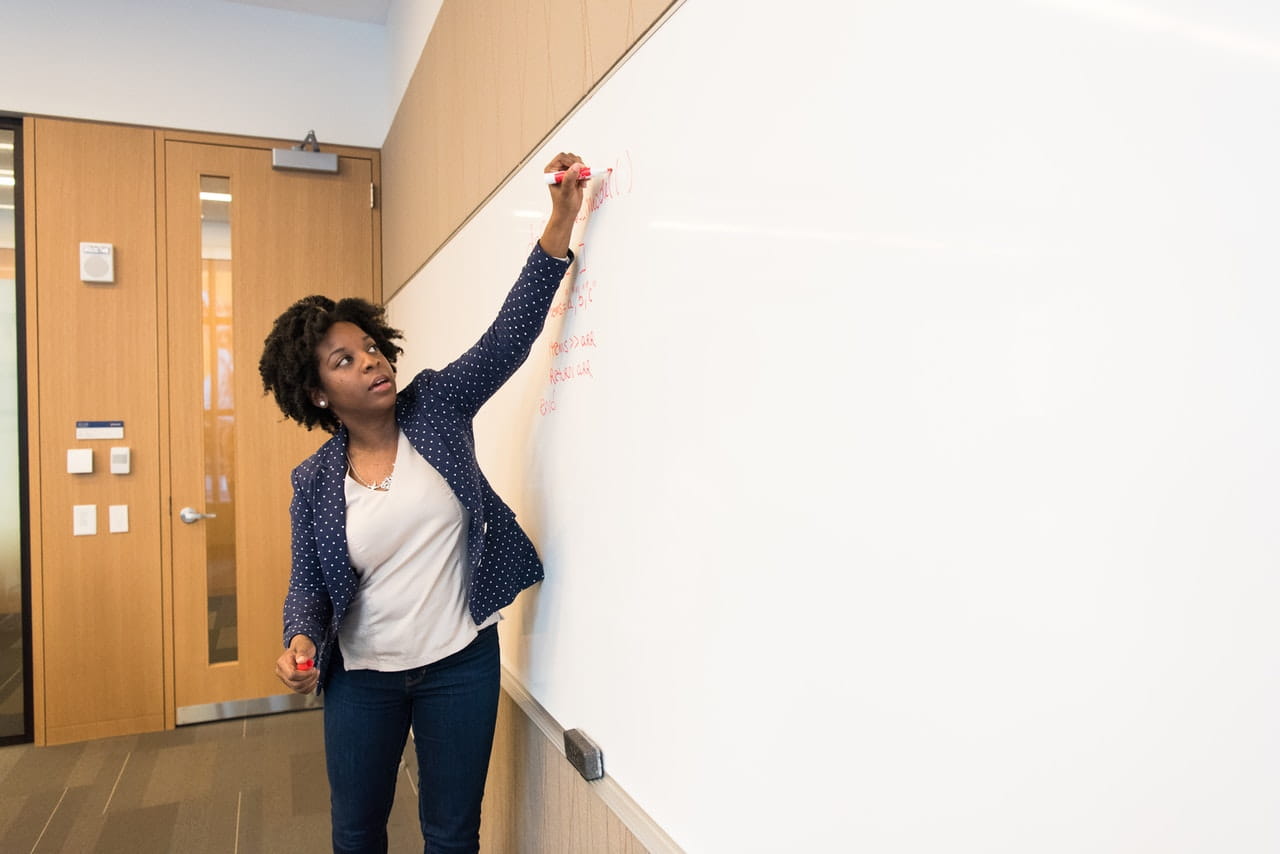 Teacher writing on a whiteboard 