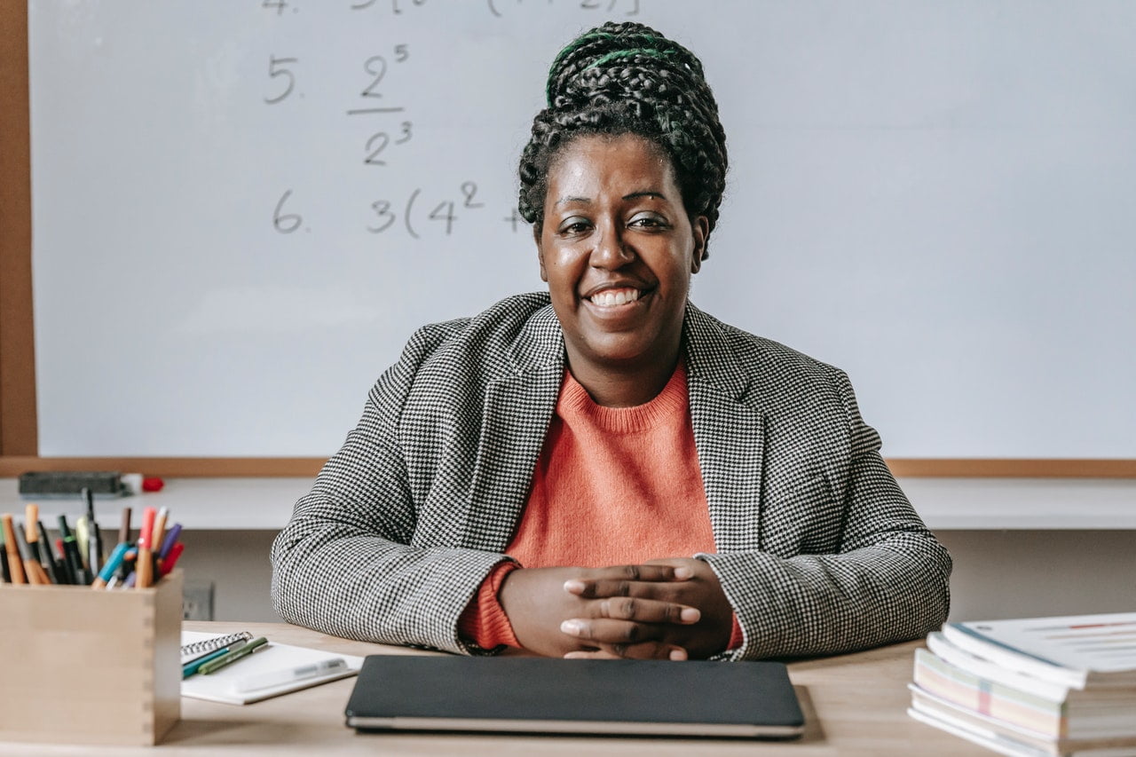 An educator sitting in a classroom and smiling for the camera. 