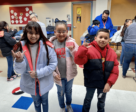 Three children at Central Elementary School in Carrollton pose for photos in their new winter coats, donated by Operation Warm