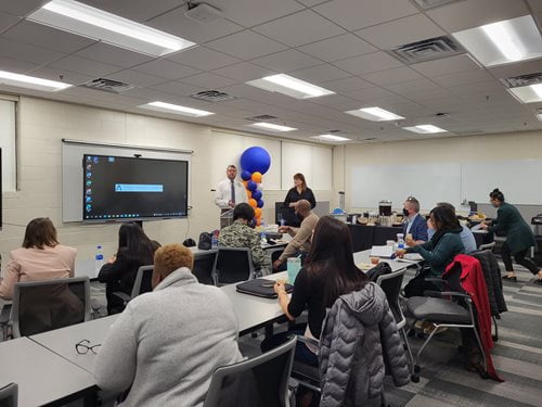 Photo of event attendees watching a presentation during the 2022 Research Day from the UTA College of Education