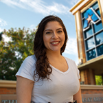 Headshot of University of Texas at Arlington employee Ashley Villegas. The background shows a UTA campus sign.