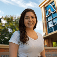 Headshot of University of Texas at Arlington employee Ashley Villegas. The background shows a UTA campus sign.