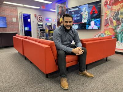 Luis Perez Cortes sitting on a large couch inside of the Basement, an e-sports space on the U T A campus where gamers compete and play video games
