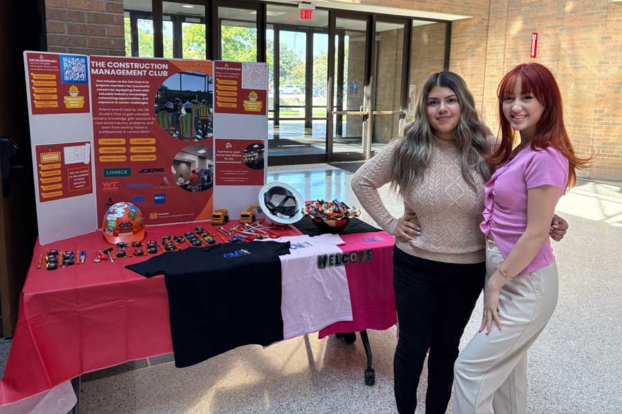 Two engineering students in front of presentation board on the construction management club.