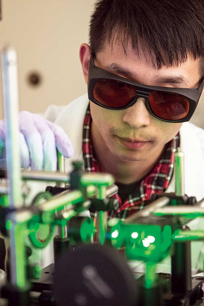 A UTA electrical engineering student works with a laser