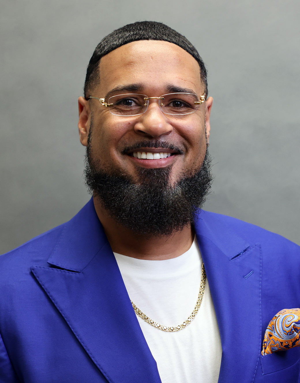 Asst. Dean Myrshem George, a bearded man wearing a bright blue jacket and glasses." _languageinserted="true