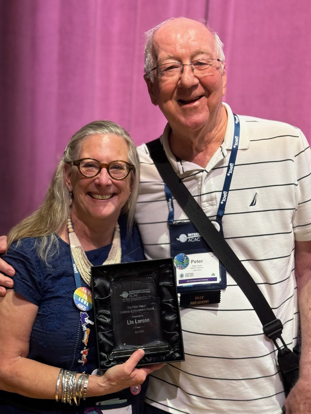 Lin Larson standing to the left of Peter Hauet while holding a dark-colored award." _languageinserted="true