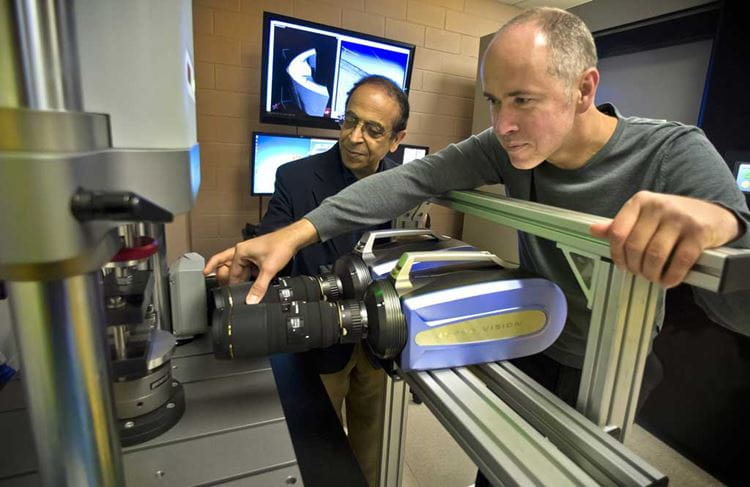 Two professors in mechanical and aerospace engineering demonstrate equipment in a research laboratory.