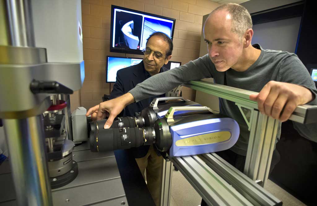 Two professors in mechanical and aerospace engineering demonstrate equipment in a research laboratory.
