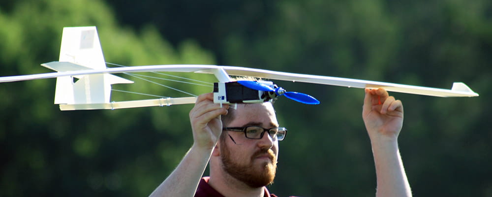 Student holding a small aircraft in the design, print, fly competition.