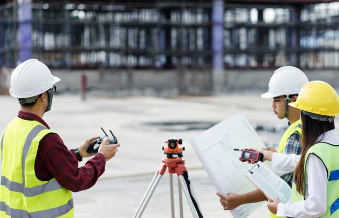 Three Civil Engineers Surveying a Construction Area